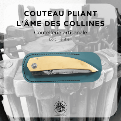 Couteau pliant artisanal intitulé "L'âme des collines" réalisé par Loïc Héritier, coutellerie artisanale. La lame en acier forgé brut de forge est finement polie, et le manche est en Buis du Luberon, offrant une prise en main ergonomique. Le couteau est posé sur un fond évoquant un atelier de forge artisanale, avec des outils en arrière-plan, mettant en valeur le savoir-faire de la coutellerie traditionnelle.