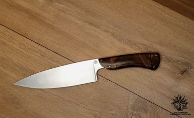 Élégance et précision définissent ce Couteau de Chef Artisanal, exposé sur un fond en bois clair qui met en valeur son esthétique raffinée. La lame, lisse et tranchante, est fabriquée en acier inoxydable X46Cr13, promettant une coupe impeccable et une résistance à la corrosion. Le manche en ronce de noyer de Provence, aux motifs tourbillonnants uniques, offre une prise en main confortable et une touche d'authenticité. La qualité de la fabrication artisanale française est mise en évidence par les rivets en acier qui accentuent l'aspect traditionnel et durable de ce couteau. Idéal pour les cuisiniers professionnels et les amateurs de gastronomie, ce couteau est un hommage à l'art culinaire.