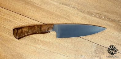 Élégance et précision définissent ce Couteau de Chef Artisanal, exposé sur un fond en bois clair qui met en valeur son esthétique raffinée. La lame, lisse et tranchante, est fabriquée en acier inoxydable X46Cr13, promettant une coupe impeccable et une résistance à la corrosion. Le manche en ronce de noyer de Provence, aux motifs tourbillonnants uniques, offre une prise en main confortable et une touche d'authenticité. La qualité de la fabrication artisanale française est mise en évidence par les rivets en acier qui accentuent l'aspect traditionnel et durable de ce couteau. Idéal pour les cuisiniers professionnels et les amateurs de gastronomie, ce couteau est un hommage à l'art culinaire.
