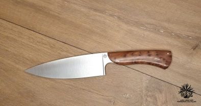 couteau de chef artisanal haut de gamme avec manche en bois du luberon . La lame est fabriquée en acier inoxydable robuste et finement affûtée, idéale pour une précision de coupe en cuisine. Le manche en bois de thuya présente des motifs de grain riches et une finition lisse avec des rivets en acier inoxydable, alliant esthétique traditionnelle et modernité. Cet outil de cuisine est à la fois fonctionnel et élégant, reflétant l'excellence de l'artisanat coutelier.