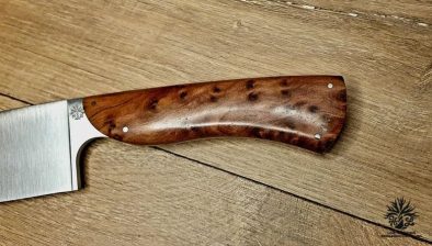 couteau de chef artisanal haut de gamme avec manche en bois du luberon . La lame est fabriquée en acier inoxydable robuste et finement affûtée, idéale pour une précision de coupe en cuisine. Le manche en bois de thuya présente des motifs de grain riches et une finition lisse avec des rivets en acier inoxydable, alliant esthétique traditionnelle et modernité. Cet outil de cuisine est à la fois fonctionnel et élégant, reflétant l'excellence de l'artisanat coutelier.