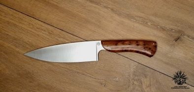 couteau de chef artisanal haut de gamme avec manche en bois du luberon . La lame est fabriquée en acier inoxydable robuste et finement affûtée, idéale pour une précision de coupe en cuisine. Le manche en bois de thuya présente des motifs de grain riches et une finition lisse avec des rivets en acier inoxydable, alliant esthétique traditionnelle et modernité. Cet outil de cuisine est à la fois fonctionnel et élégant, reflétant l'excellence de l'artisanat coutelier.