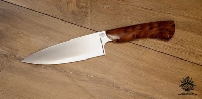 couteau de chef artisanal haut de gamme avec manche en bois du luberon . La lame est fabriquée en acier inoxydable robuste et finement affûtée, idéale pour une précision de coupe en cuisine. Le manche en bois de thuya présente des motifs de grain riches et une finition lisse avec des rivets en acier inoxydable, alliant esthétique traditionnelle et modernité. Cet outil de cuisine est à la fois fonctionnel et élégant, reflétant l'excellence de l'artisanat coutelier.