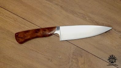 couteau de chef artisanal haut de gamme avec manche en bois du luberon . La lame est fabriquée en acier inoxydable robuste et finement affûtée, idéale pour une précision de coupe en cuisine. Le manche en bois de thuya présente des motifs de grain riches et une finition lisse avec des rivets en acier inoxydable, alliant esthétique traditionnelle et modernité. Cet outil de cuisine est à la fois fonctionnel et élégant, reflétant l'excellence de l'artisanat coutelier.