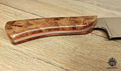 couteau de chef artisanal haut de gamme avec manche en bois du luberon . La lame est fabriquée en acier inoxydable robuste et finement affûtée, idéale pour une précision de coupe en cuisine. Le manche en bois de thuya présente des motifs de grain riches et une finition lisse avec des rivets en acier inoxydable, alliant esthétique traditionnelle et modernité. Cet outil de cuisine est à la fois fonctionnel et élégant, reflétant l'excellence de l'artisanat coutelier.